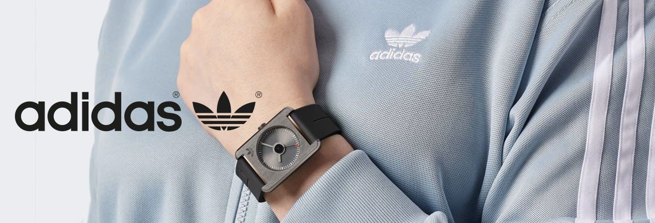 vrouw in een lichtblauw adidas trainingsjack die een retro adidas horloge draagt