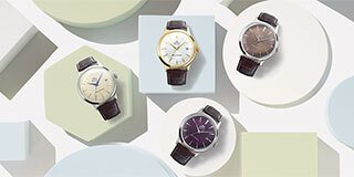Four Orient Bambino watches on pastel colored blocks