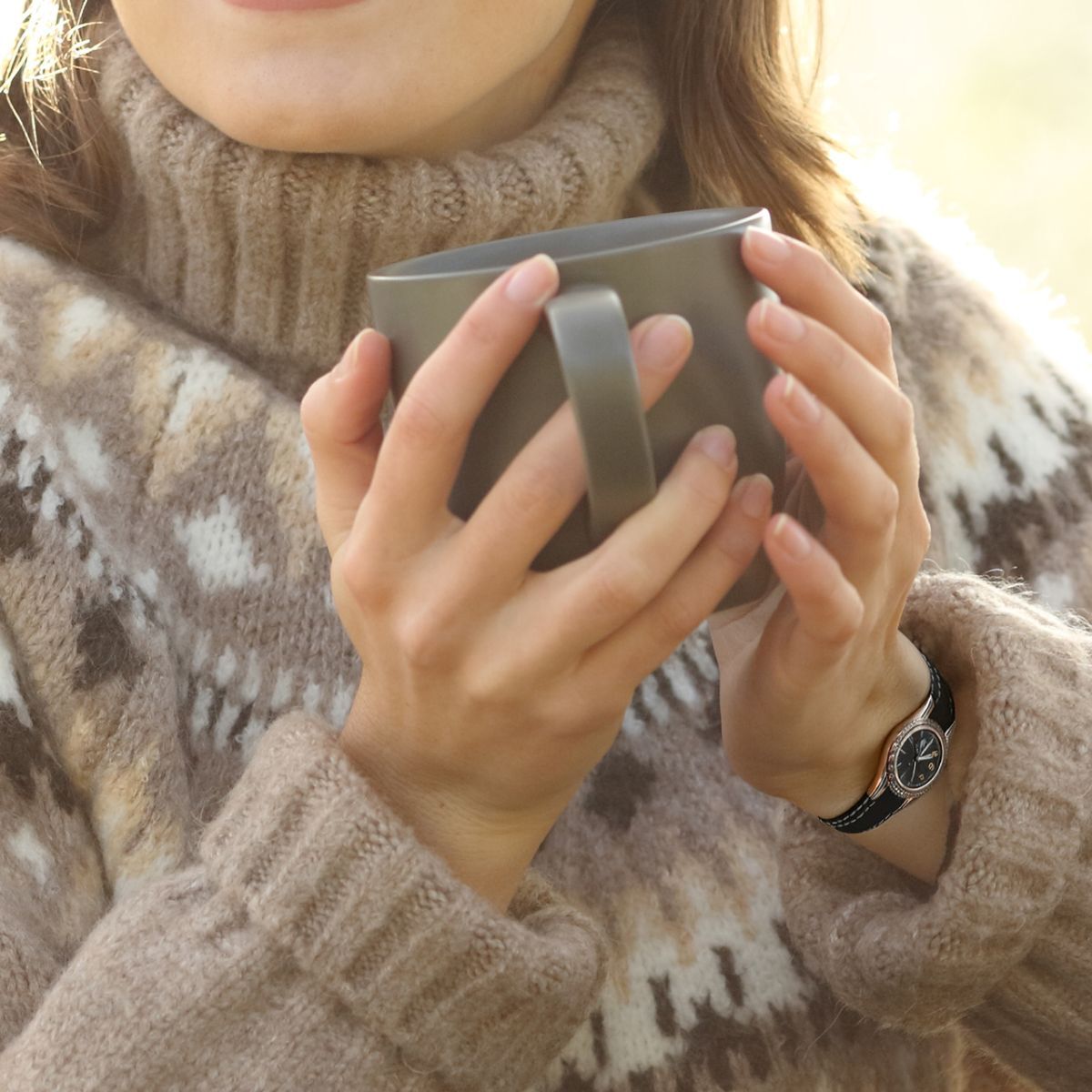 manos de mujer con uñas rojas sosteniendo una taza de té y llevando un jersey de navidad