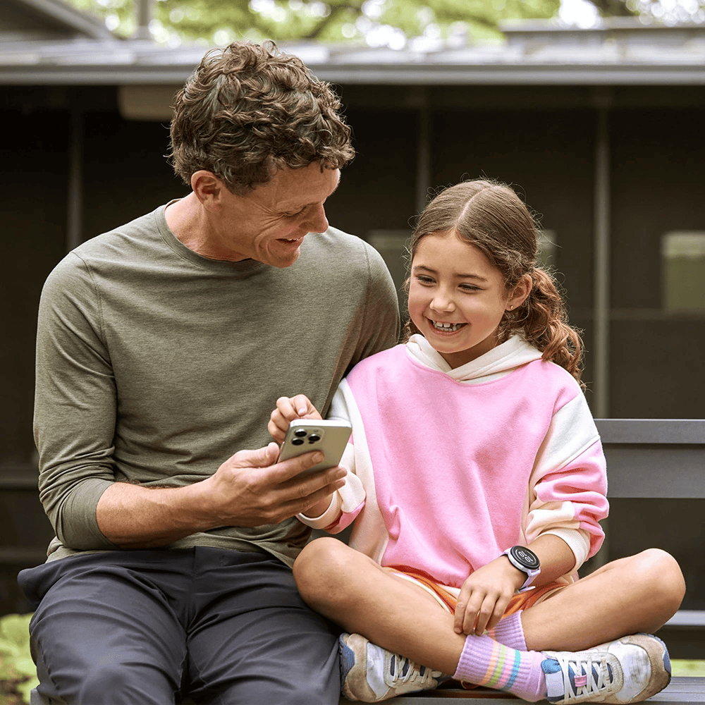Een vader die zijn dochter iets op zijn mobiele telefoon laat zien