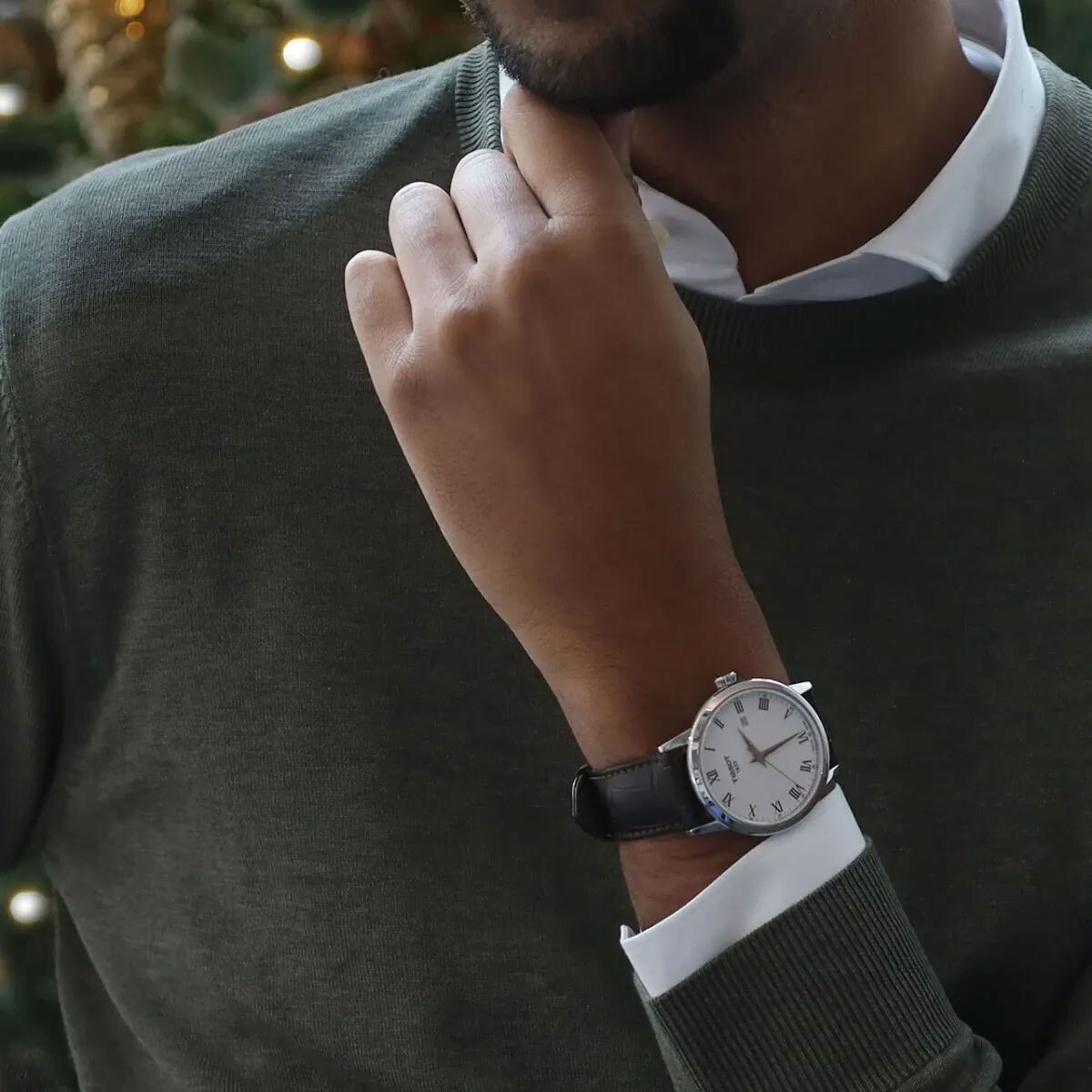 Torso und Hand eines jungen schwarzen Mannes, der einen grünen Pullover und eine klassische Herrenuhr trägt