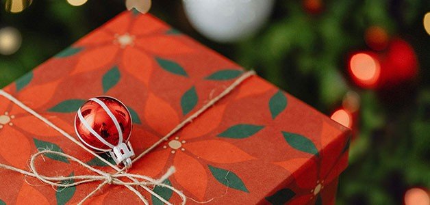 un cadeau de noël avec un arbre de noël en arrière-plan