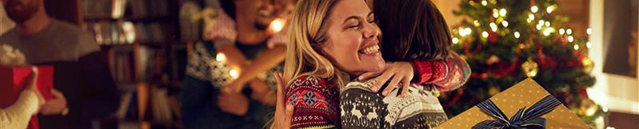 deux femmes en pulls de noël s'embrassent