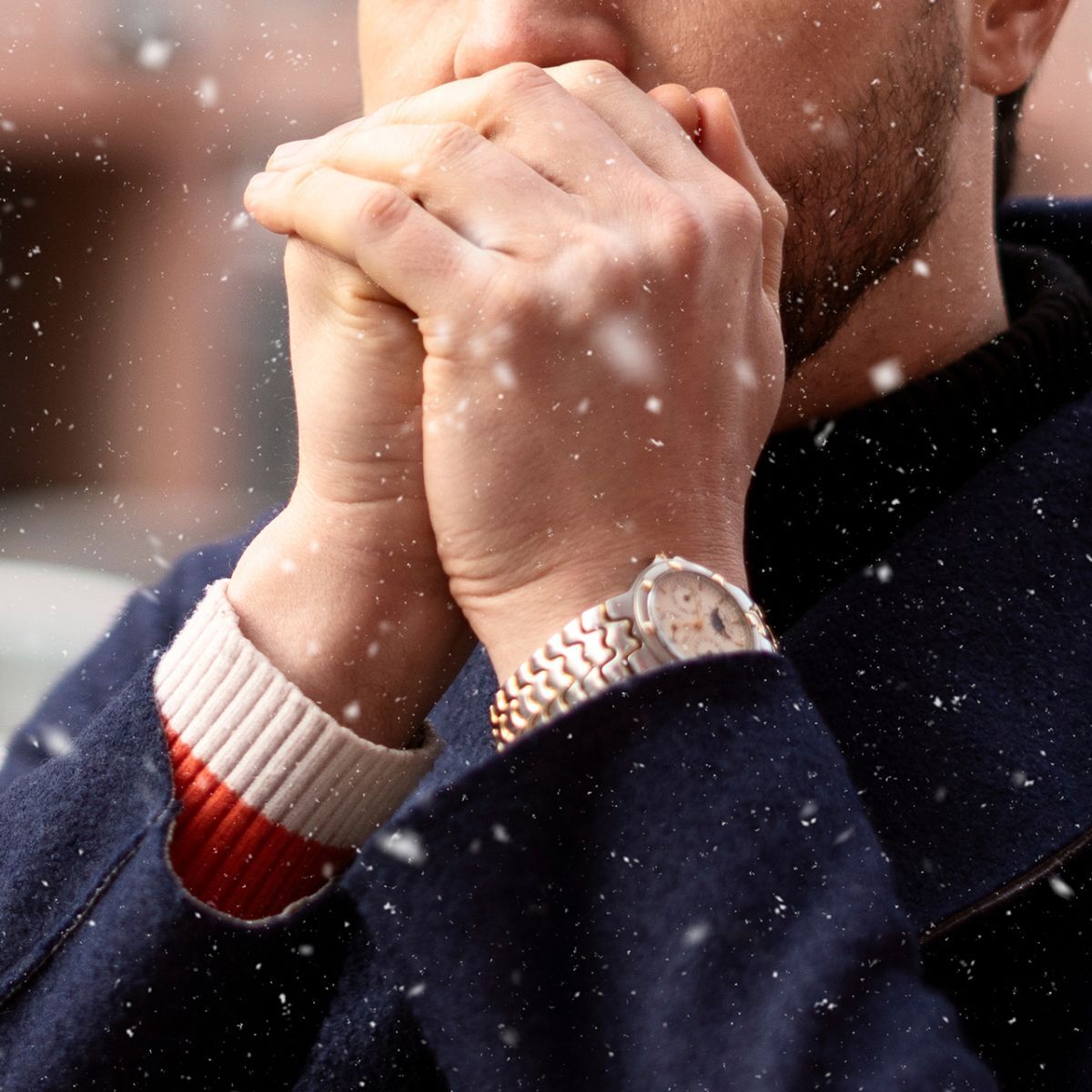 Torso y mano de un joven negro con jersey verde y reloj clásico de caballero.