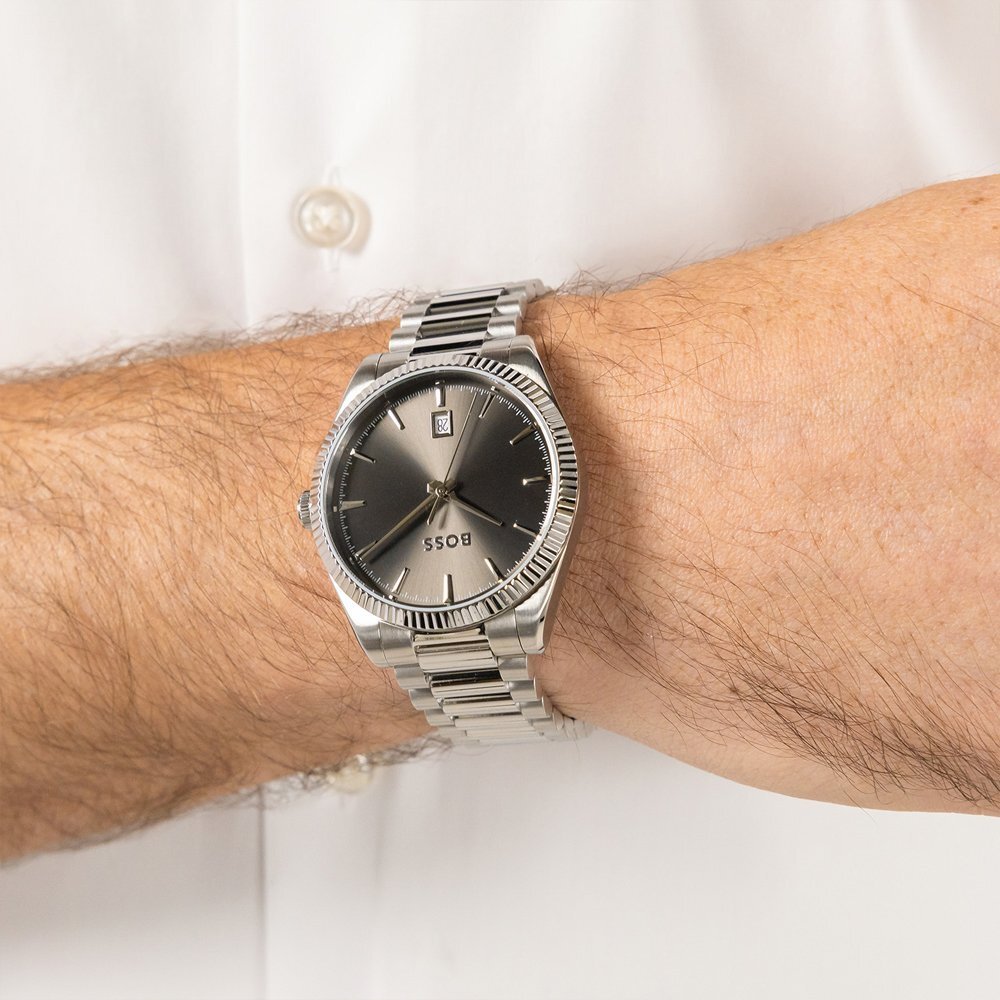 A man's hairy wrist wearing a Hugo Boss watch with a sunray dial
