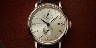 Four Orient Bambino watches on pastel colored blocks