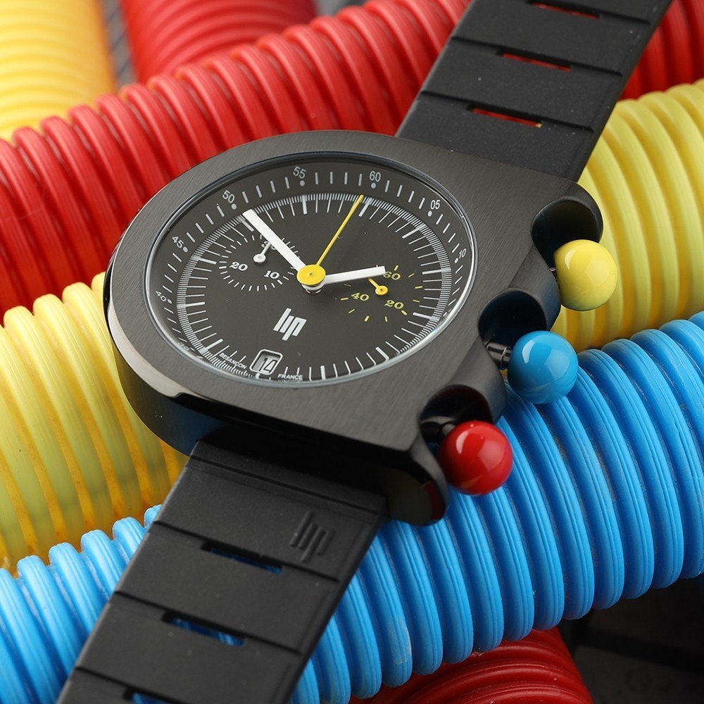 Montre LIP Mach 2000 présentée sur des tubes colorés