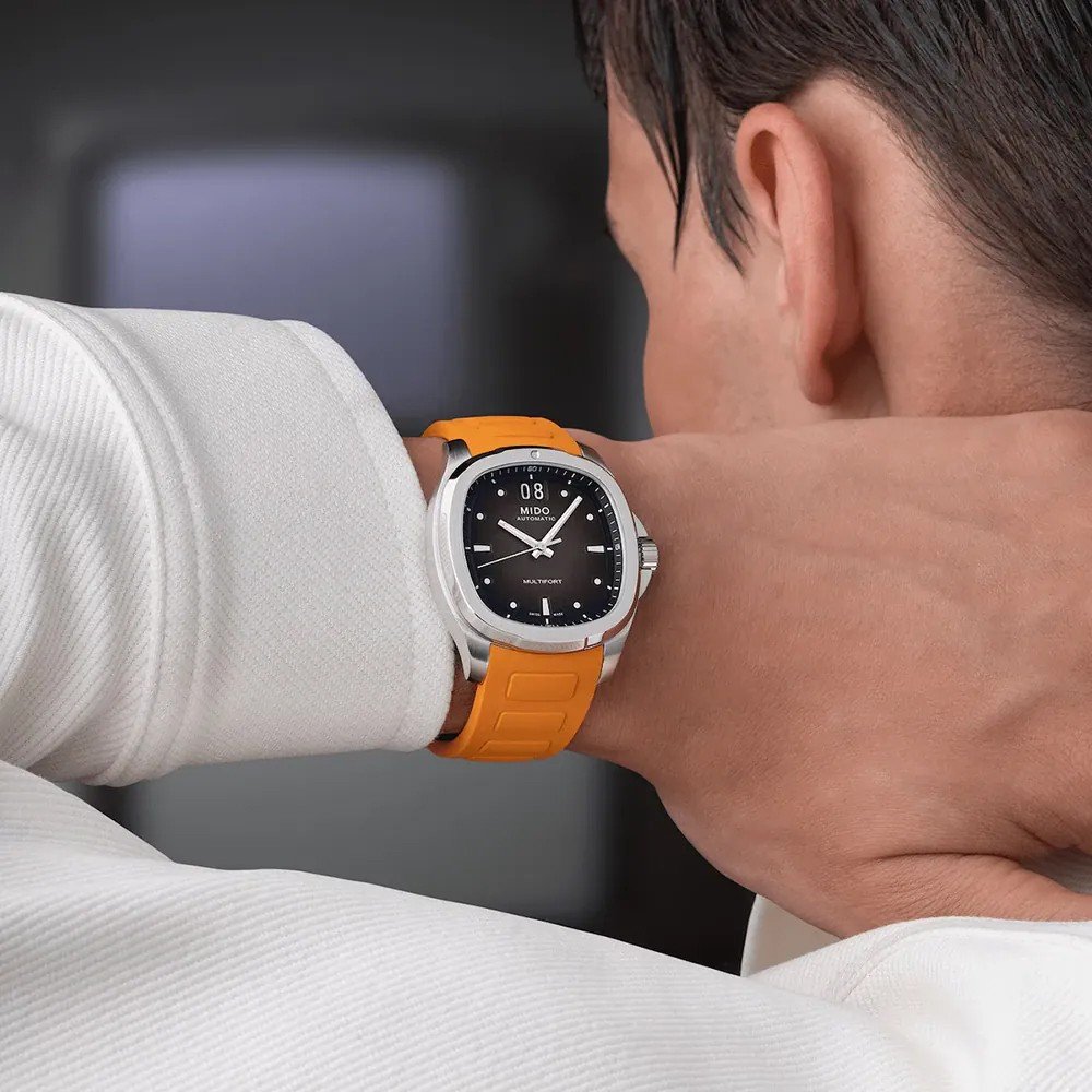 Man wearing a Mido Multifort TV Big Date M0495261708100 watch with orange rubber strap
