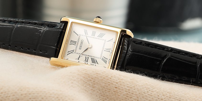 Gold toned rectangular seiko watch on a cream woolen sweater