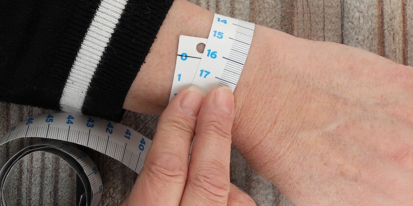 A woman's wrist with a tape measure around it