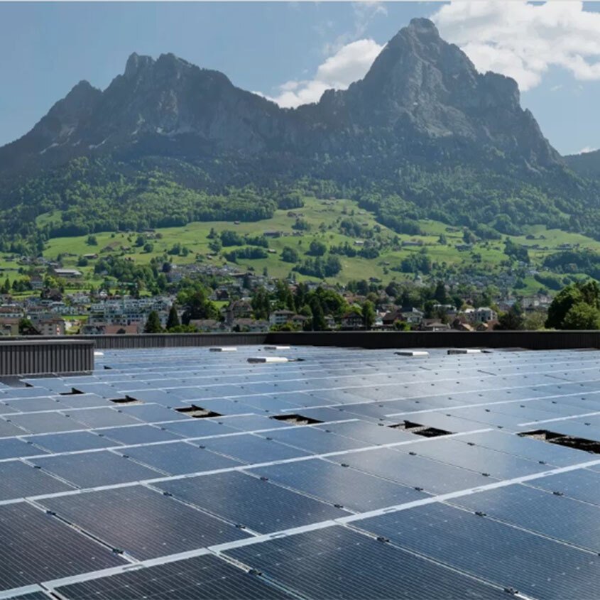 a roof with solar panels. swiss mountains in the background.