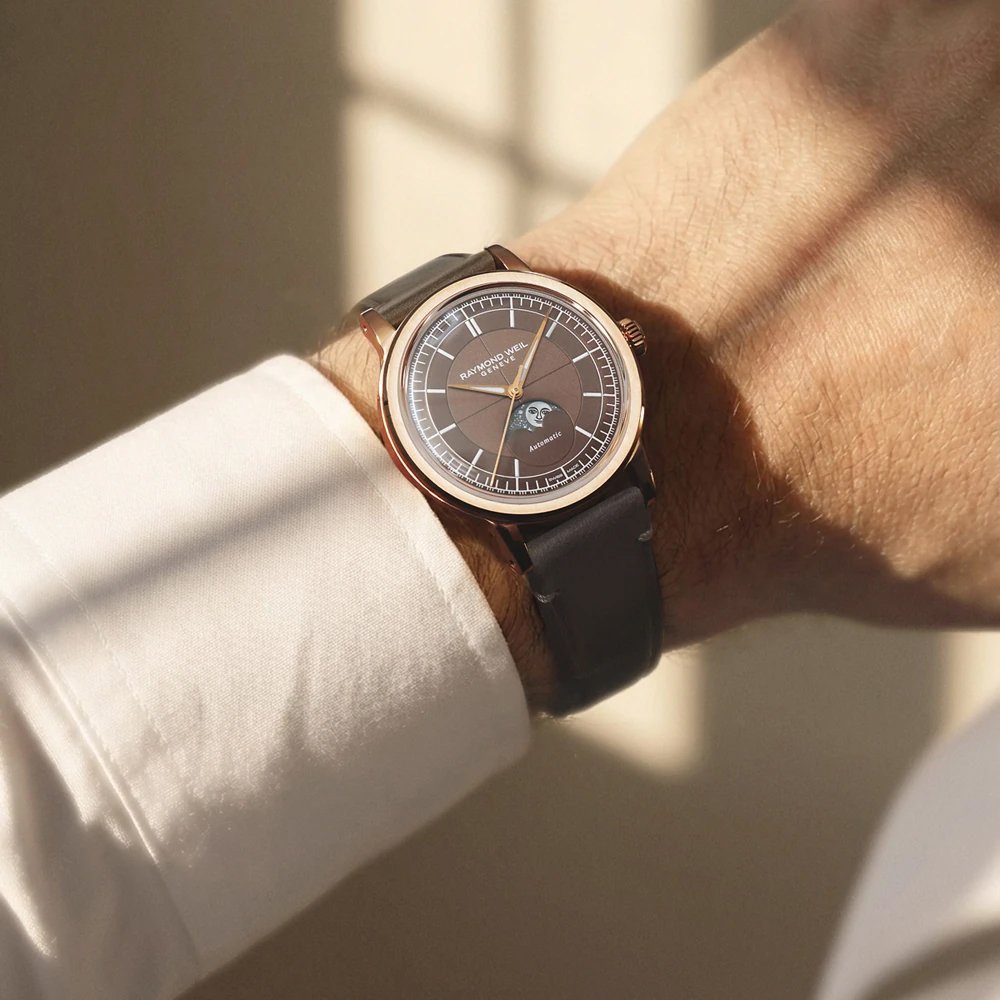 a man's writ wearing a brown raymond weil watch
