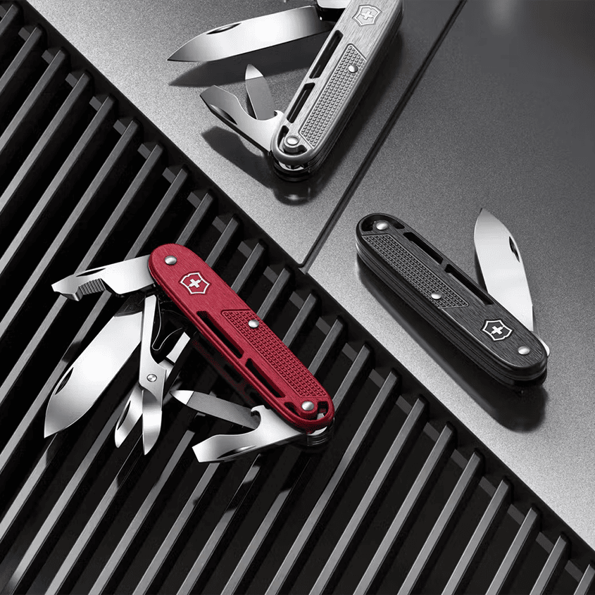 a silver, a red and a black victorinox pocket knife with the tools pulled out